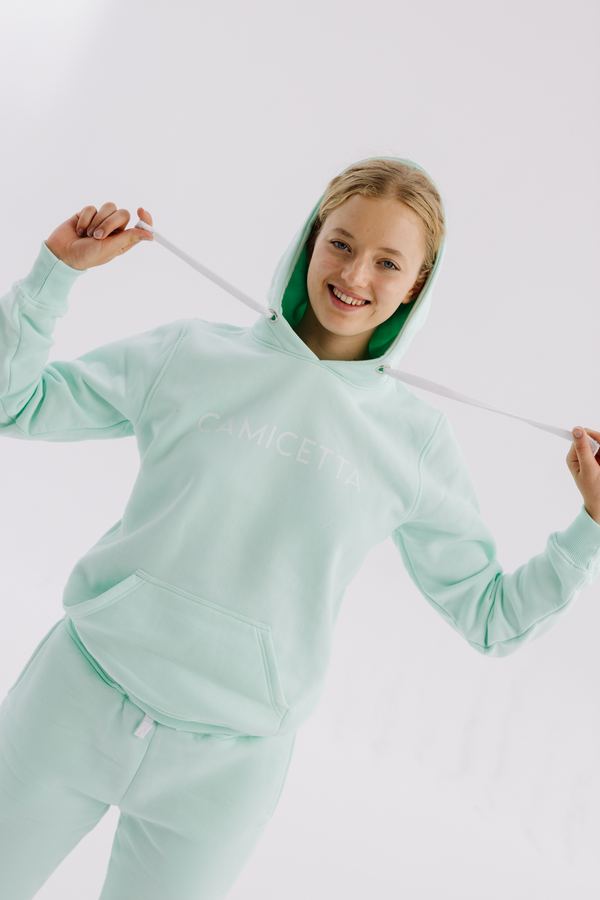 Modelka w miętowej bluzie z kapturem z zieloną podszewką kaptura