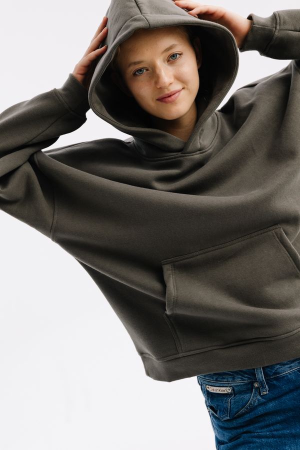 Modelka w bluzie oversize w kolorze khaki z kapturem na głowie