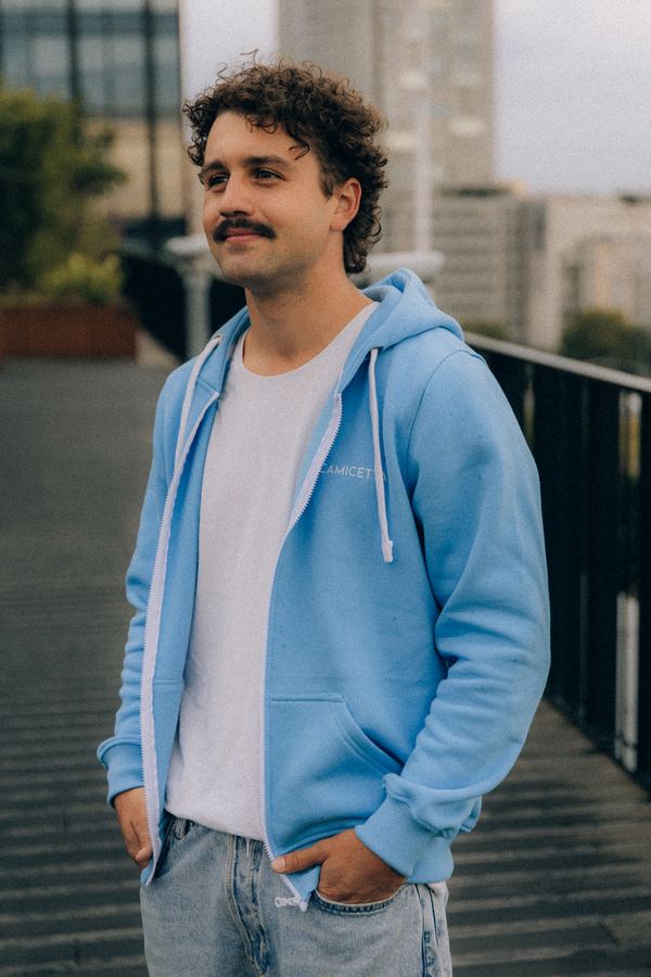 Mężczyzna w błękitnej bluzie rozpinanej z kapturem w miejskiej scenerii