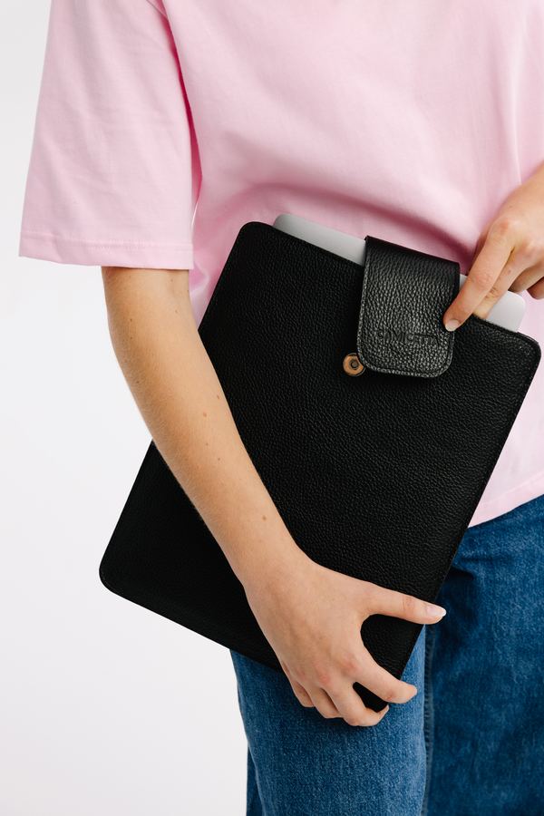 Czarne etui na laptopa trzymane przez modelkę w różowej koszulce