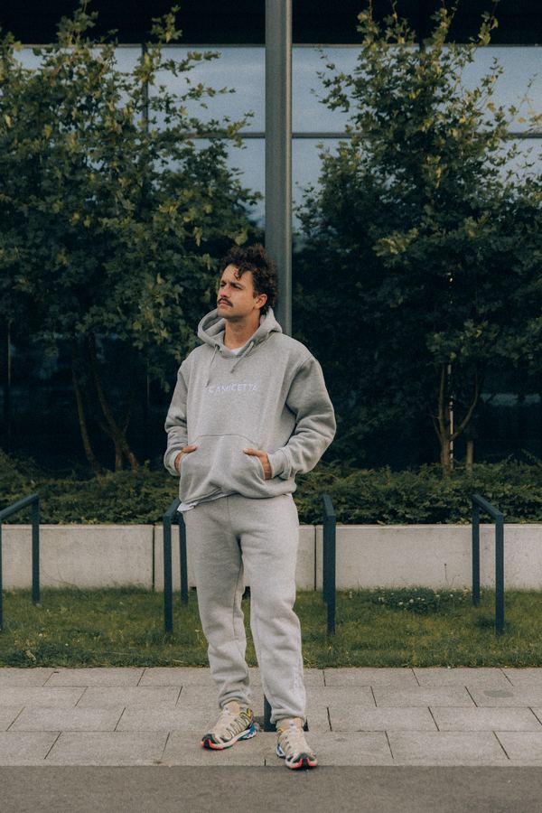 Szary komplet dresowy – bluza z kapturem i spodnie – w miejskiej scenerii