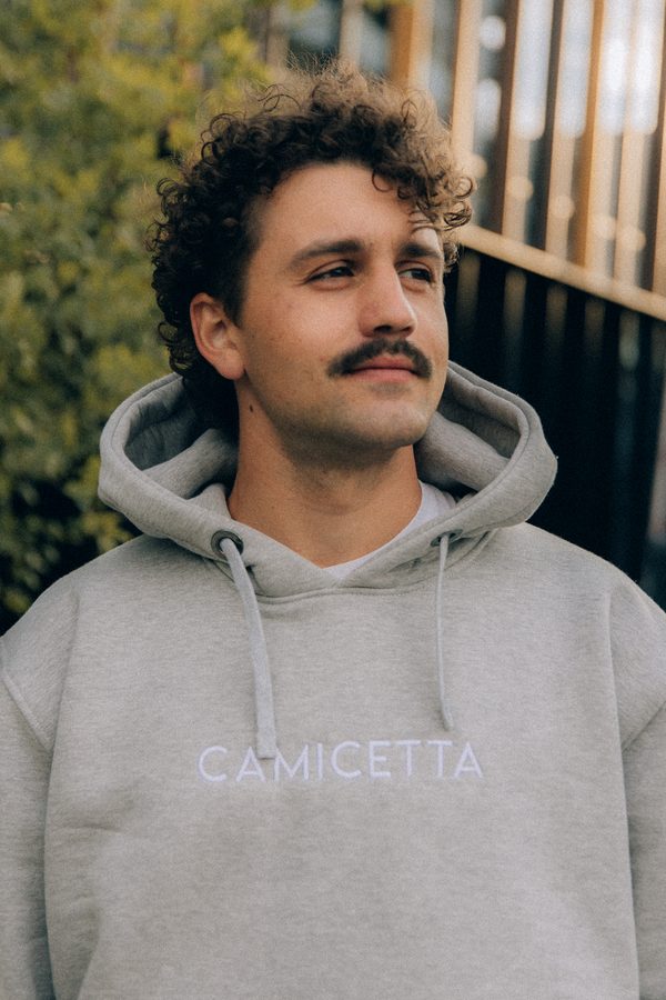 Mężczyzna w szarej bluzie z kapturem z logo Camicetta